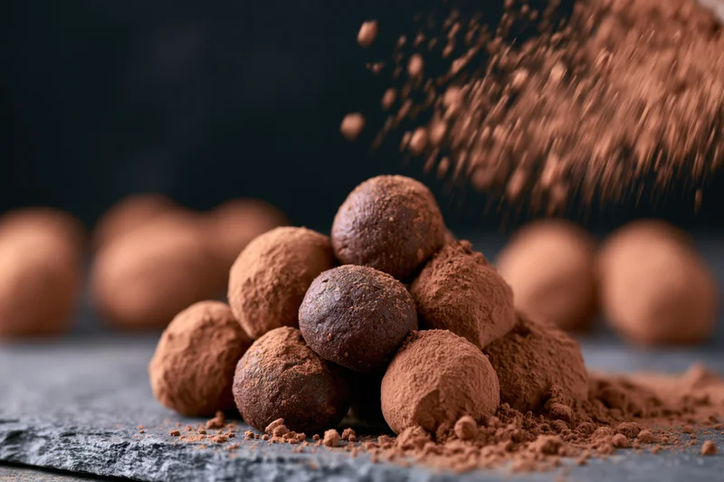 Cocoa powder dusted over a small pile of round chocolates