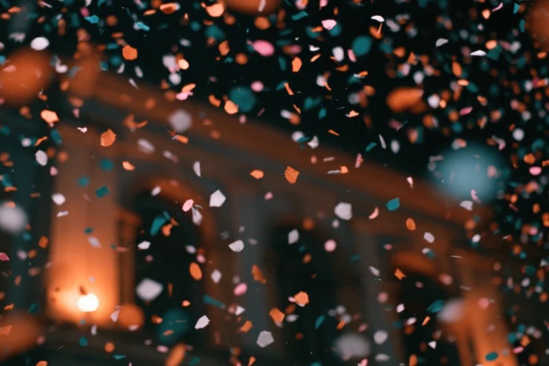 Colorful confetti pieces falling mid-air in front of a blurred building at night