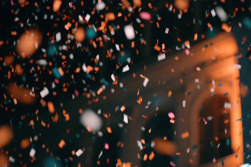 Colorful confetti falling in mid-air against a blurred building facade