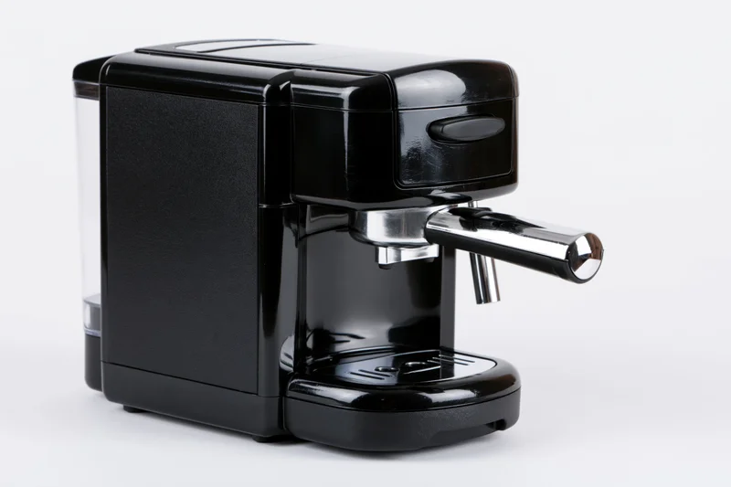 Compact black espresso machine with chrome portafilter handle on white background