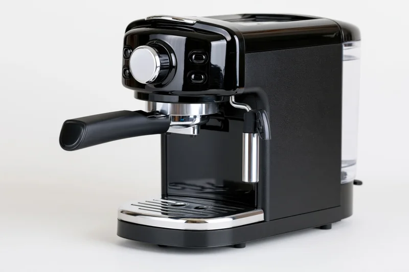 Compact black espresso machine with chrome portafilter handle on white background