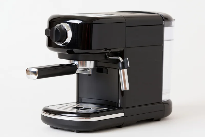 Compact black espresso machine with chrome portafilter handle on white background