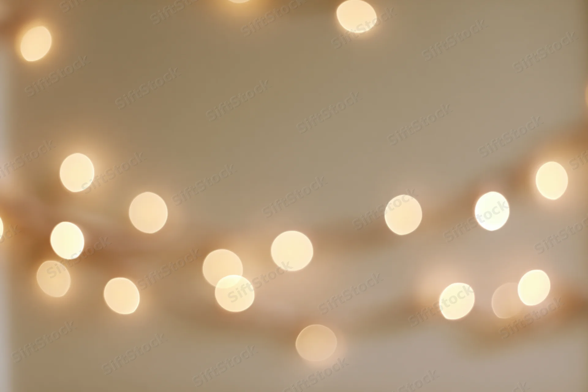 Warm fairy lights blurred into soft bokeh against a neutral wall background