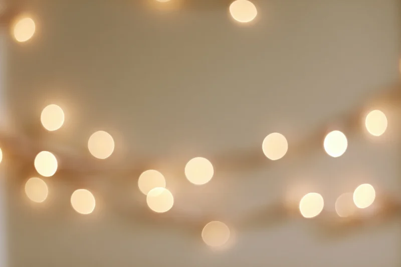 Warm fairy lights blurred into soft bokeh against a neutral wall background