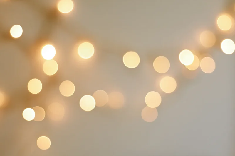 Warm fairy lights blurred against a neutral wall creating a soft glowing background