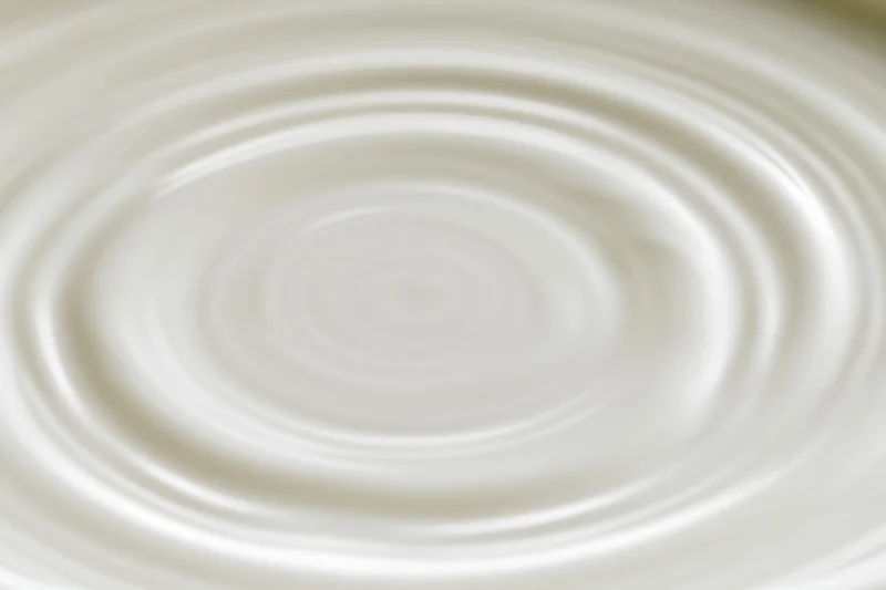 Concentric ripples spreading across the surface of white milk