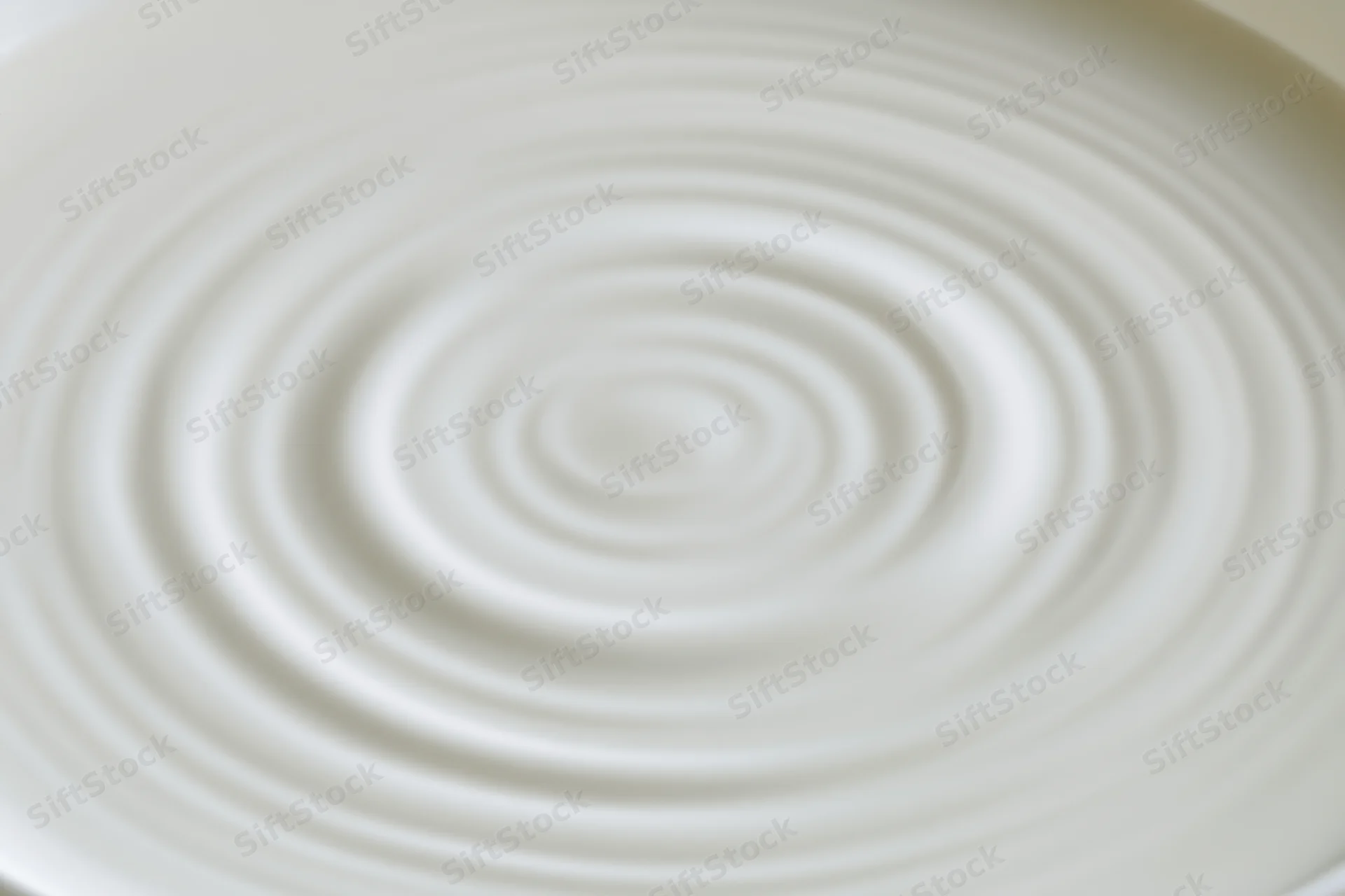 Concentric ripples spreading across the surface of white milk in a bowl