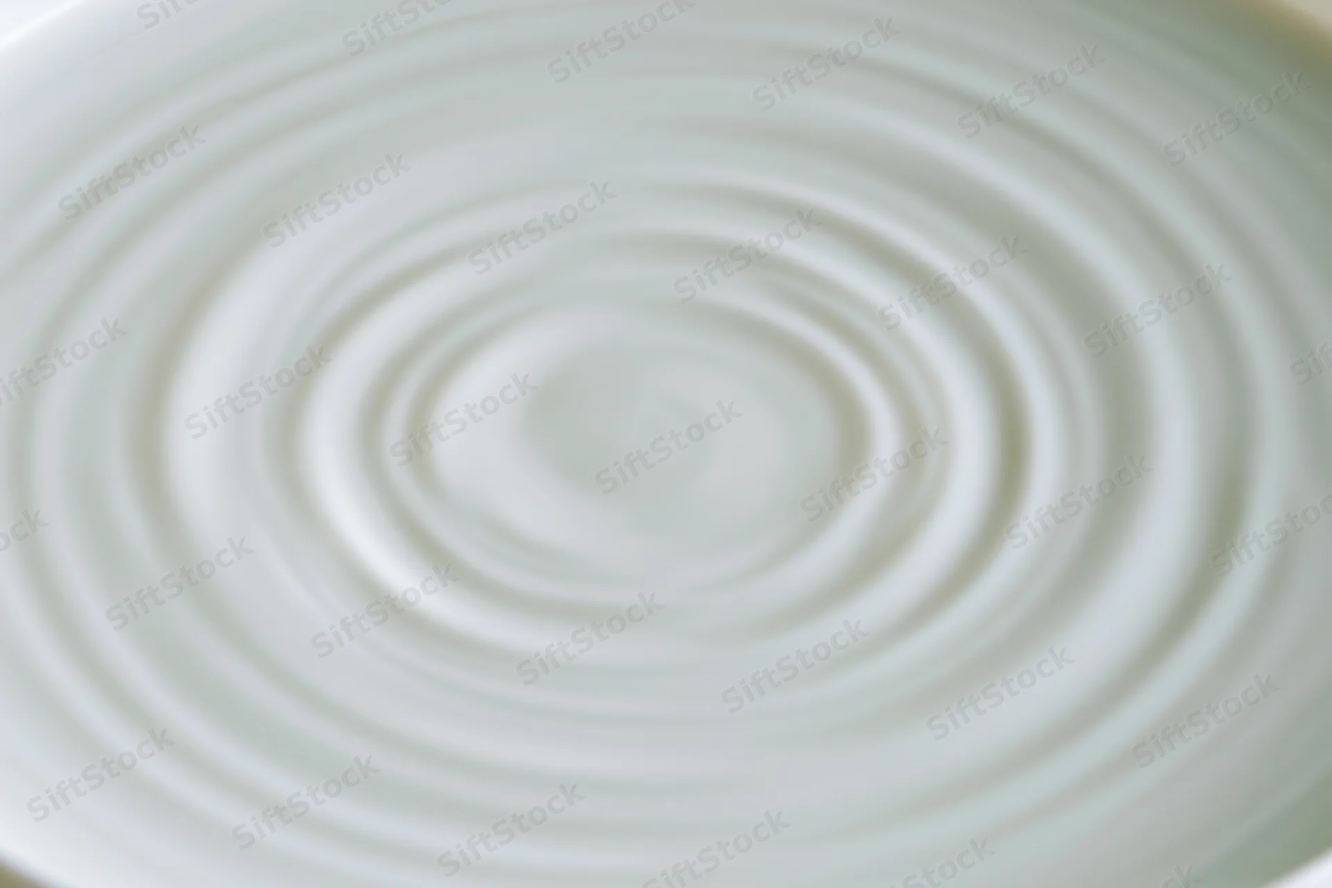 Concentric ripples spreading across the surface of white milk in a bowl