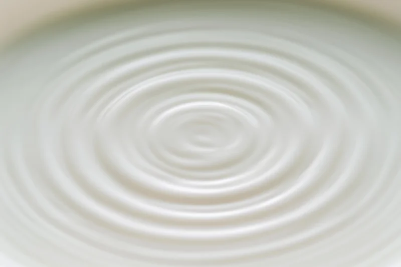 Concentric ripples spreading across the surface of white milk