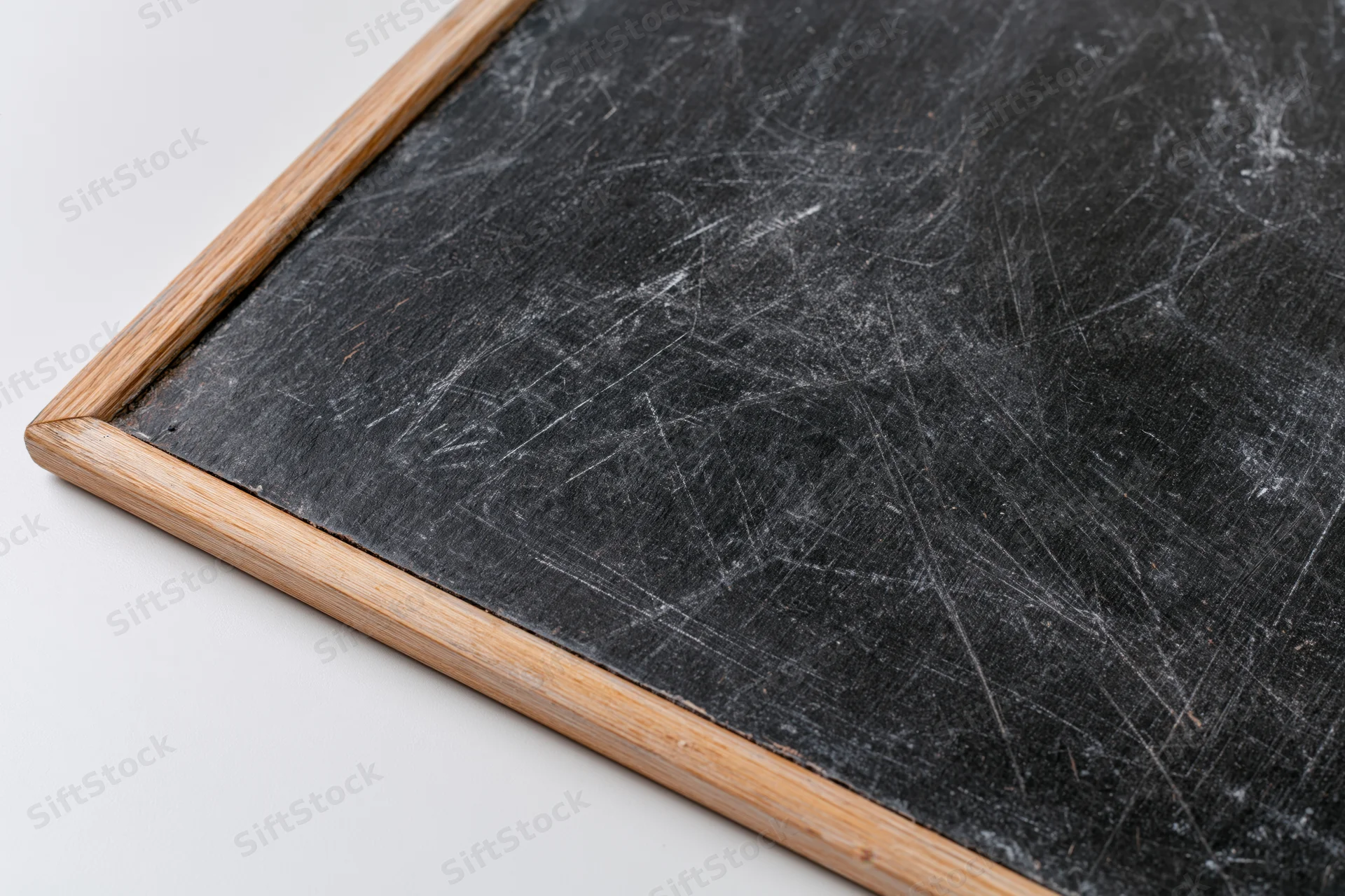 Corner of a worn chalkboard with white scratches and wooden frame on white background