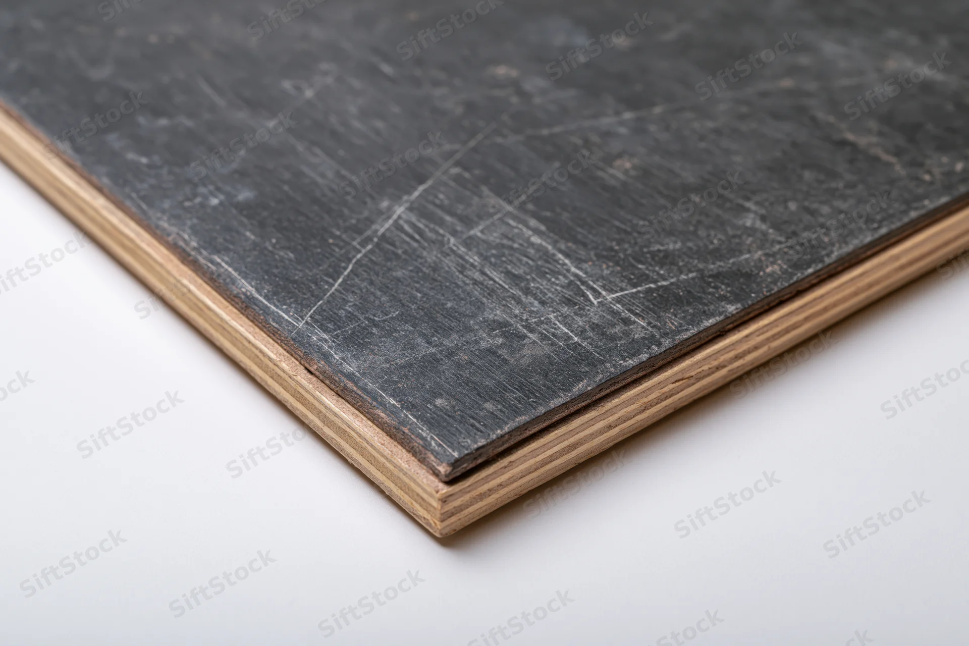 Corner of a worn black slate chalkboard panel with visible scratches and wood edge on white background