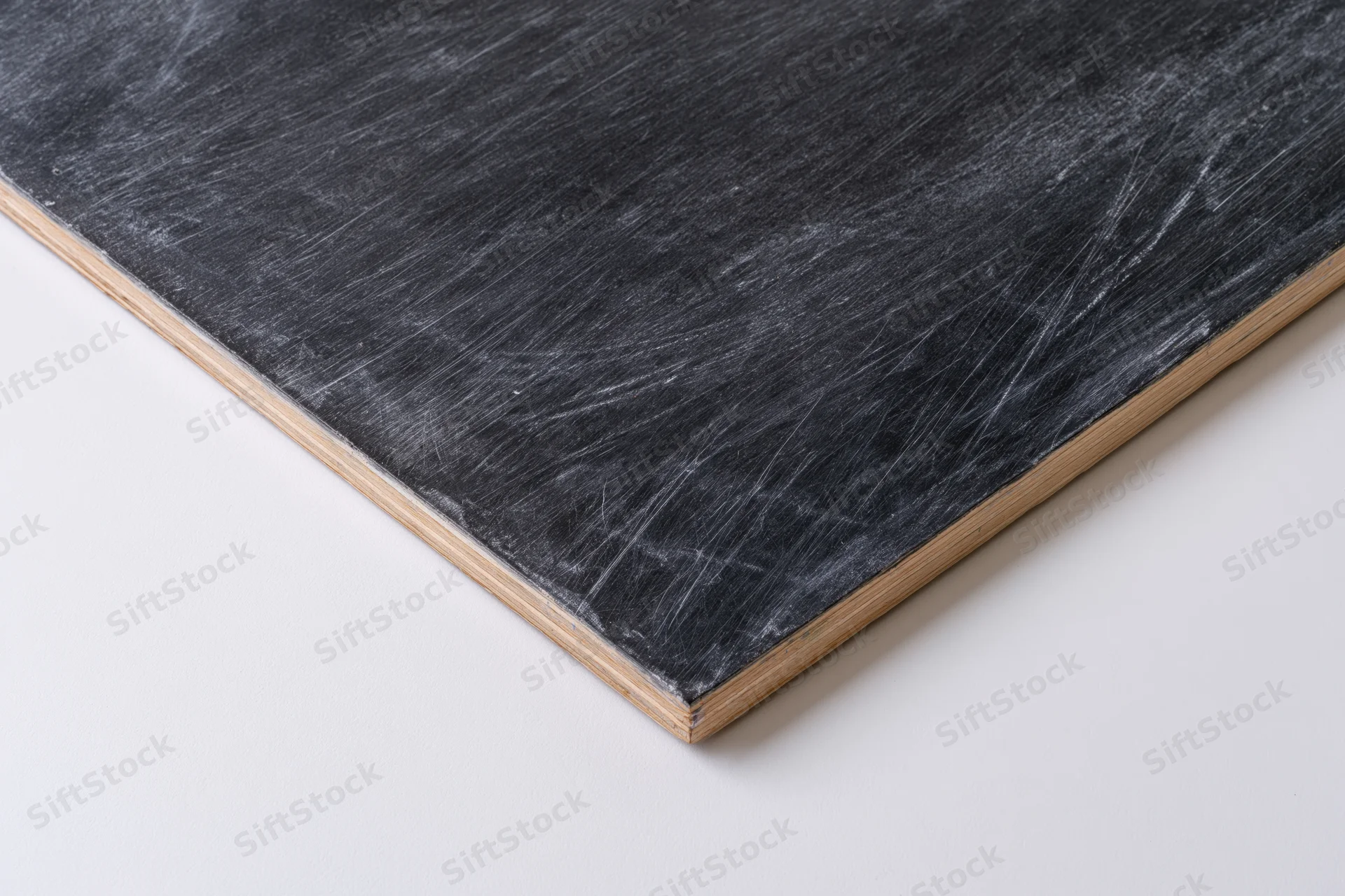 Corner of a worn chalkboard with white marks on dark surface, framed in wood, on white background