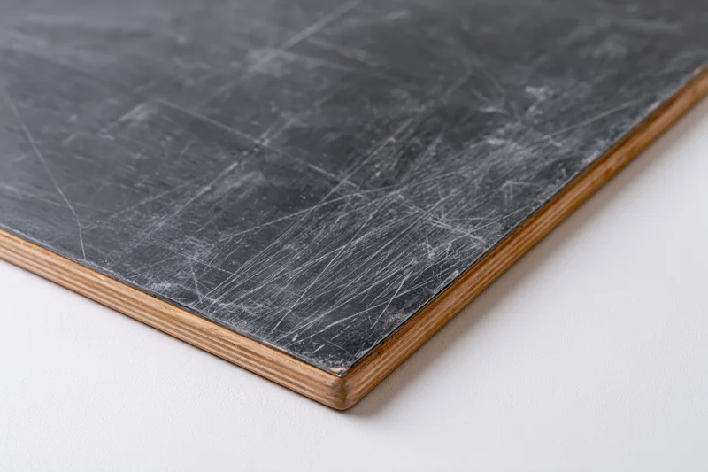Corner of a worn chalkboard with white residue and wooden frame on plain surface