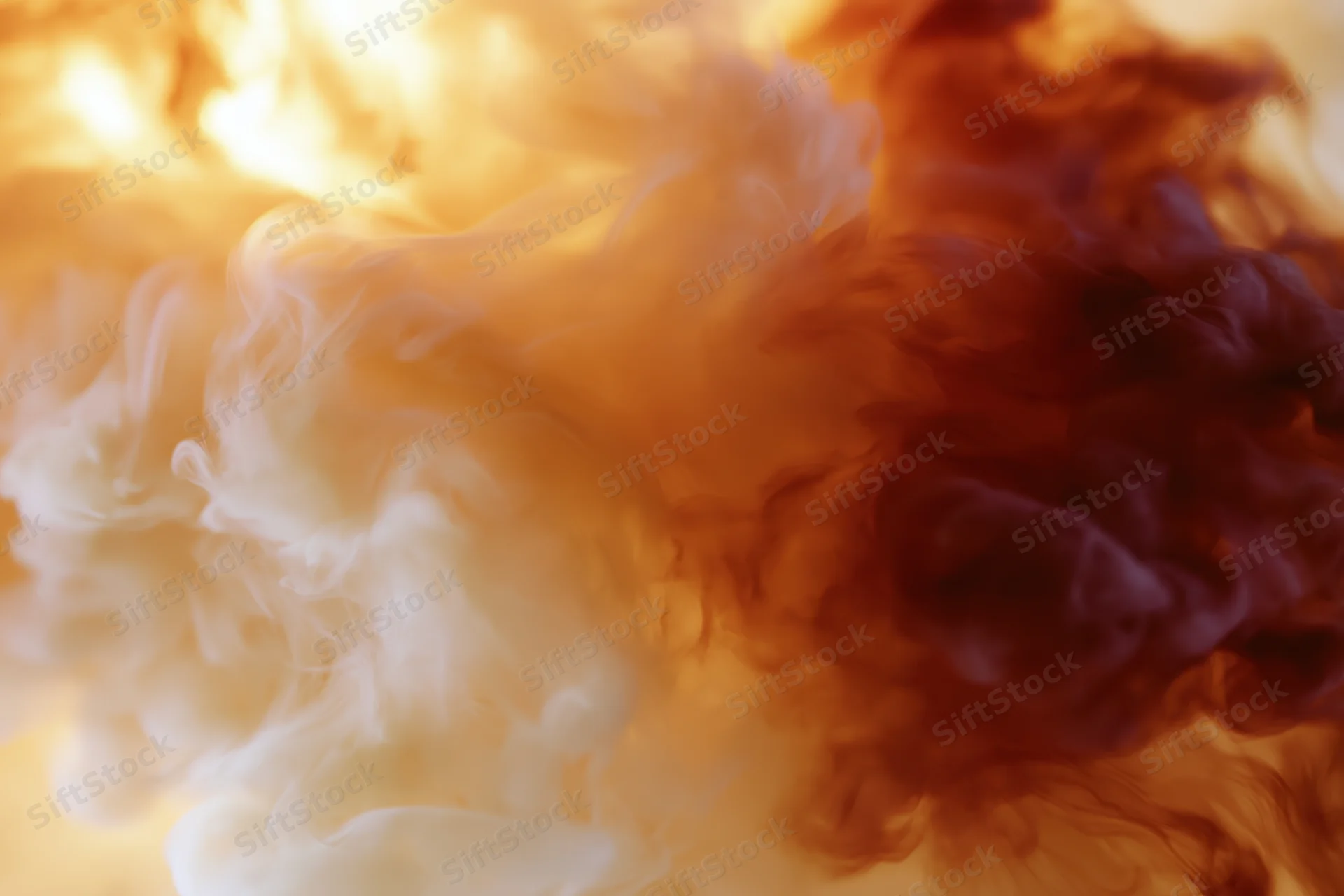 Swirling cream and amber ink dispersing in water creating abstract smoke-like patterns