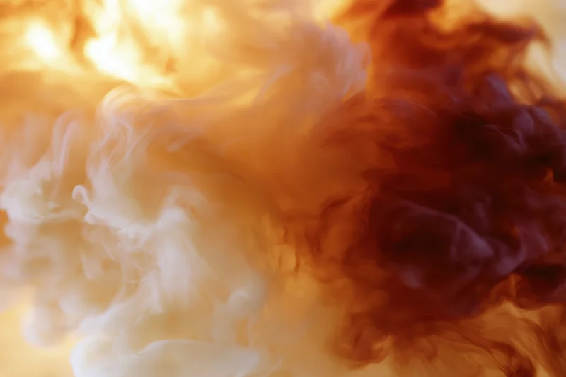 Swirling cream and amber ink dispersing in water creating abstract smoke-like patterns