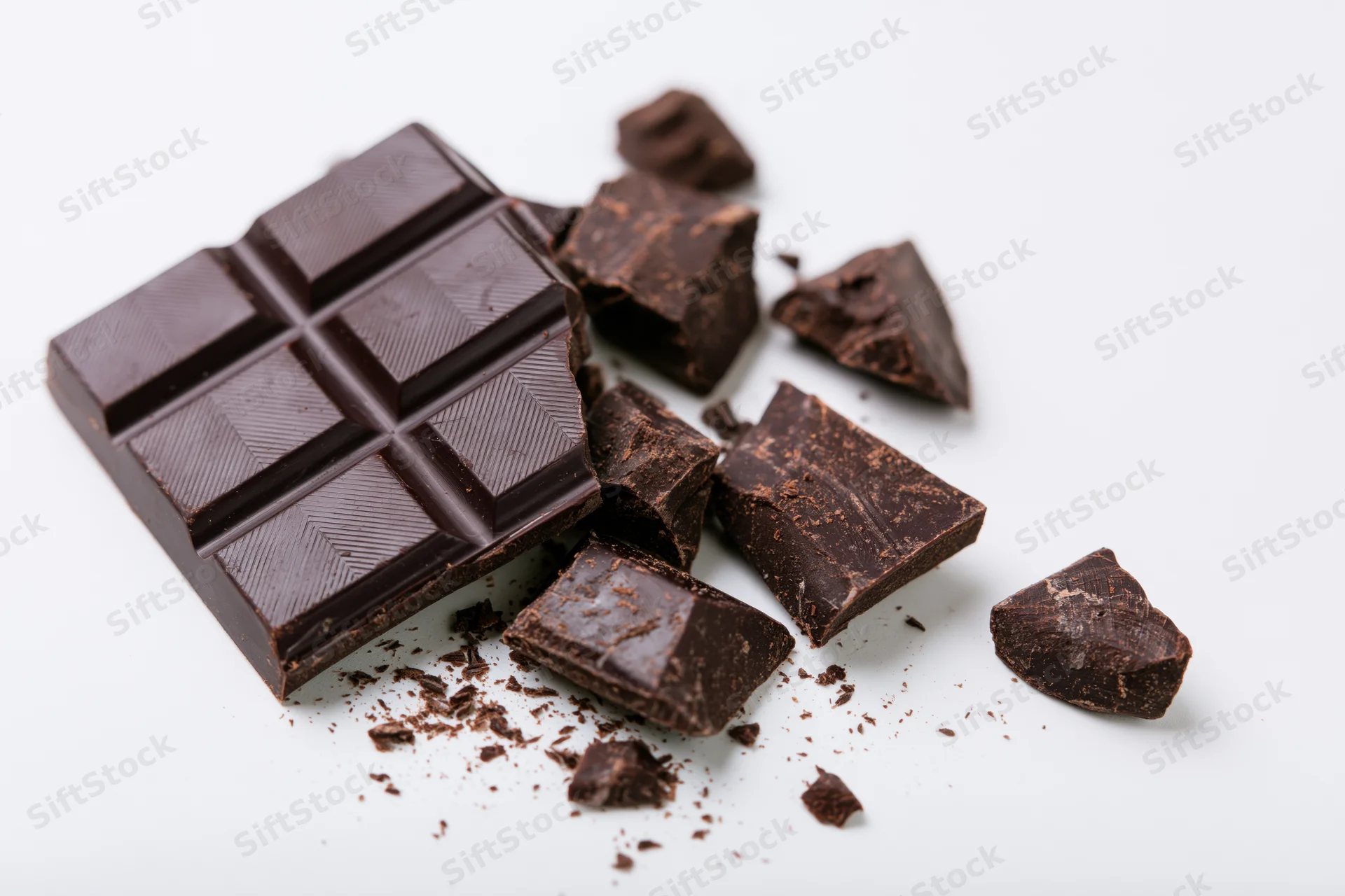 Dark chocolate bar broken into pieces on white background