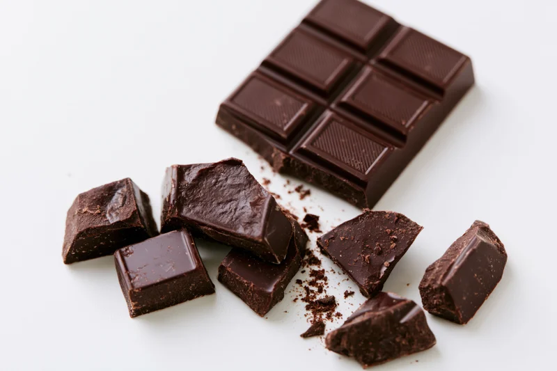 Dark chocolate bar broken into pieces on white background