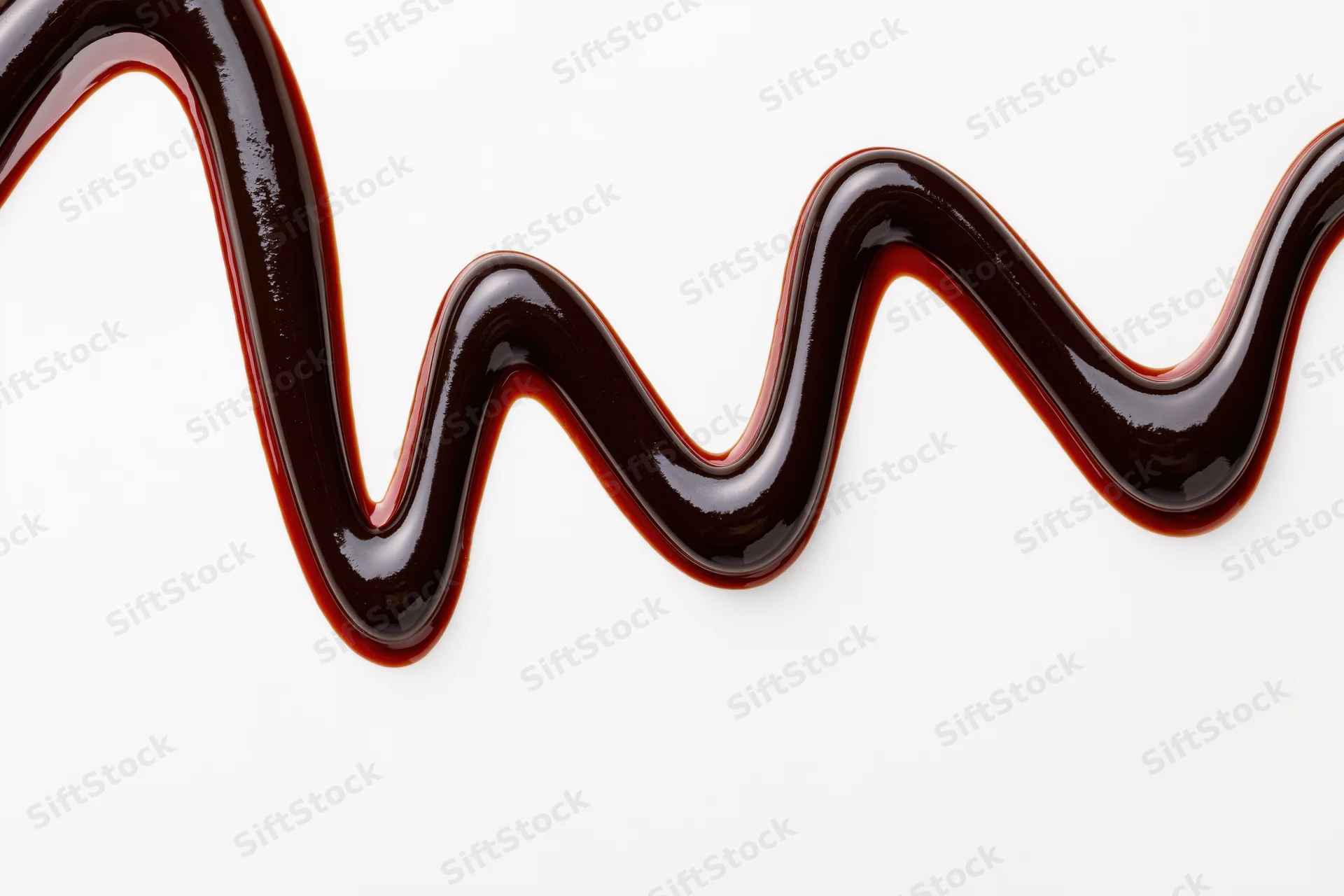 Dark chocolate sauce drizzled in a flowing zigzag pattern on white background
