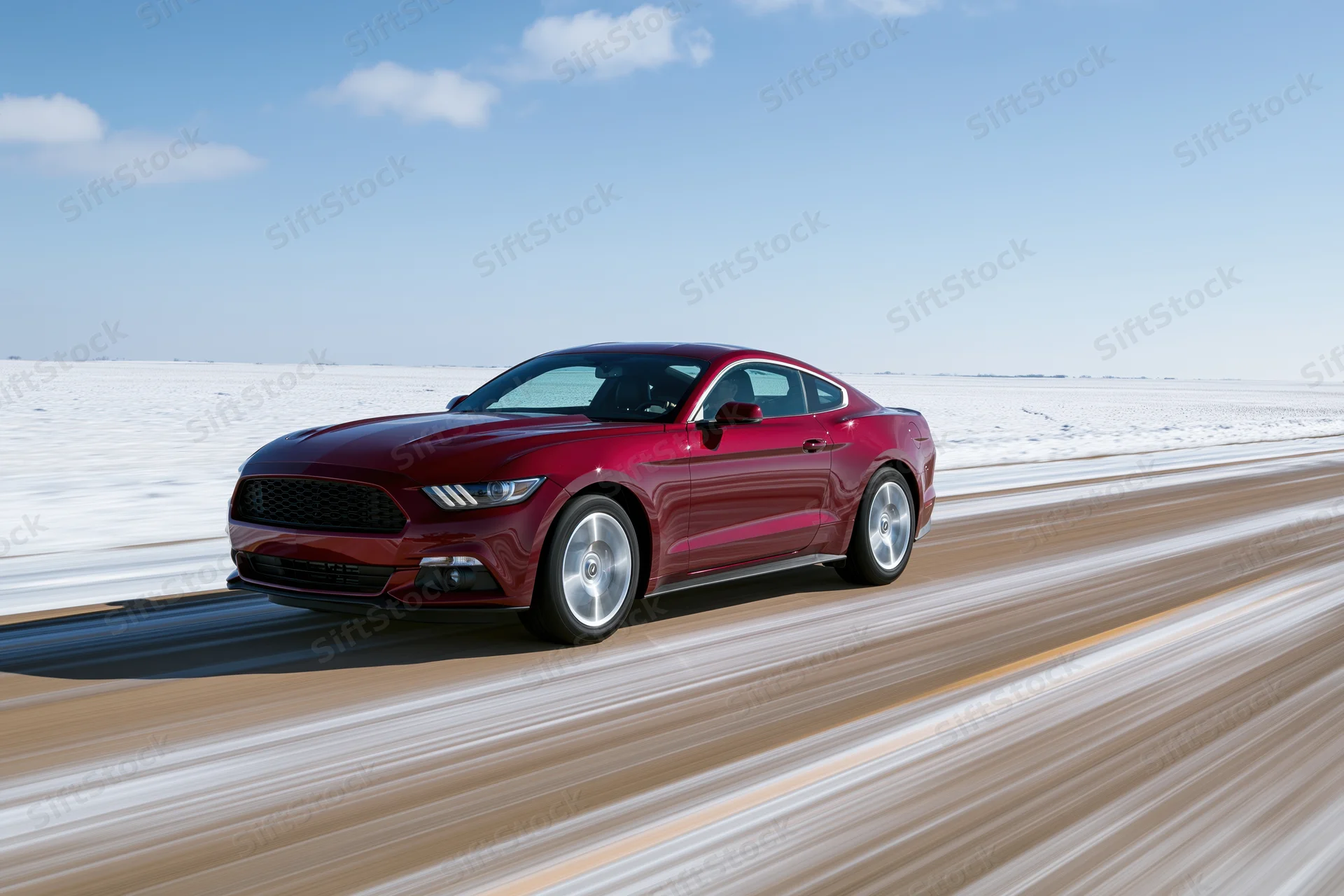 Red mustang muscle coupe driving fast on a snowy road with motion blur