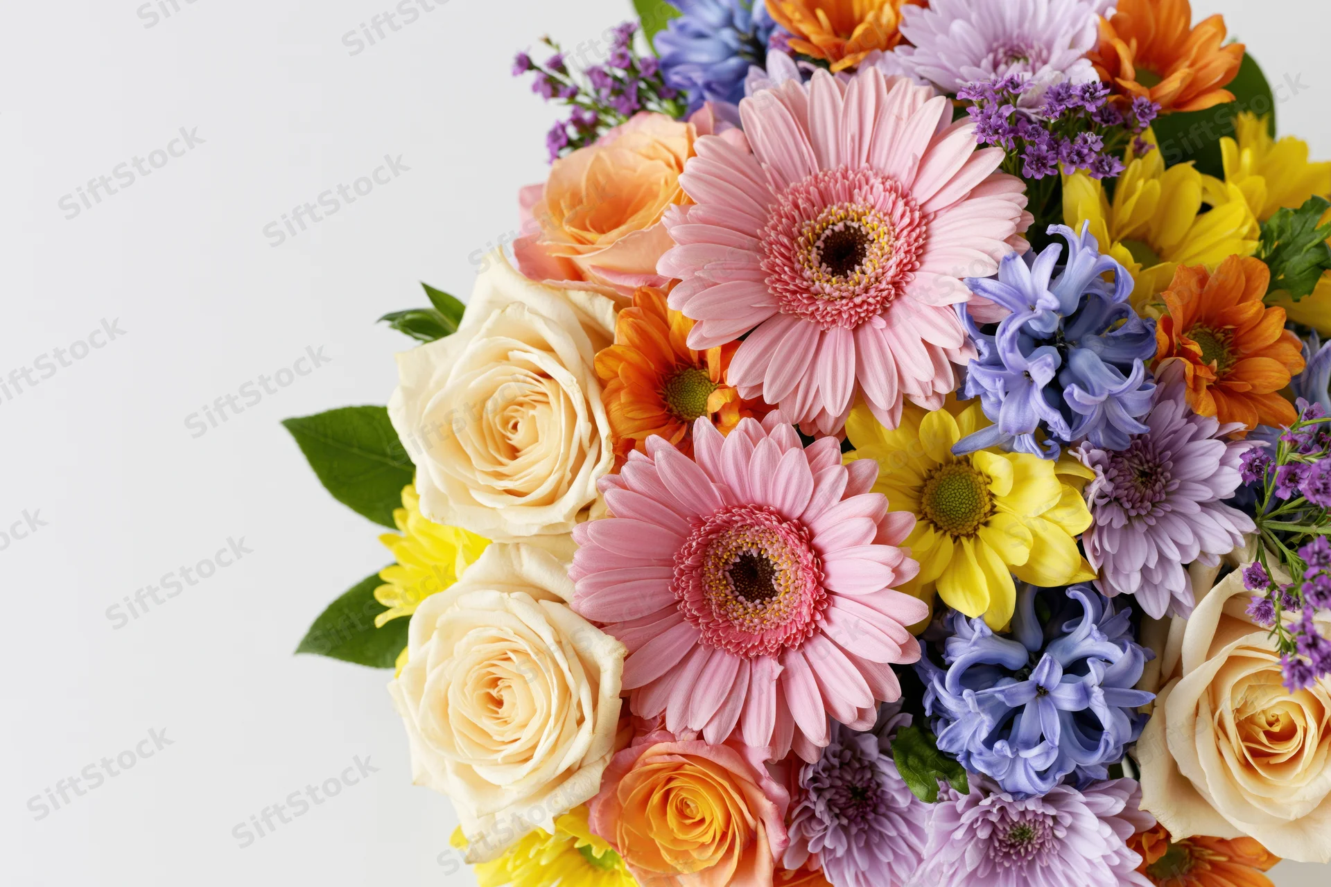 Dense mixed flower arrangement clustered along the left edge with copyspace on the right