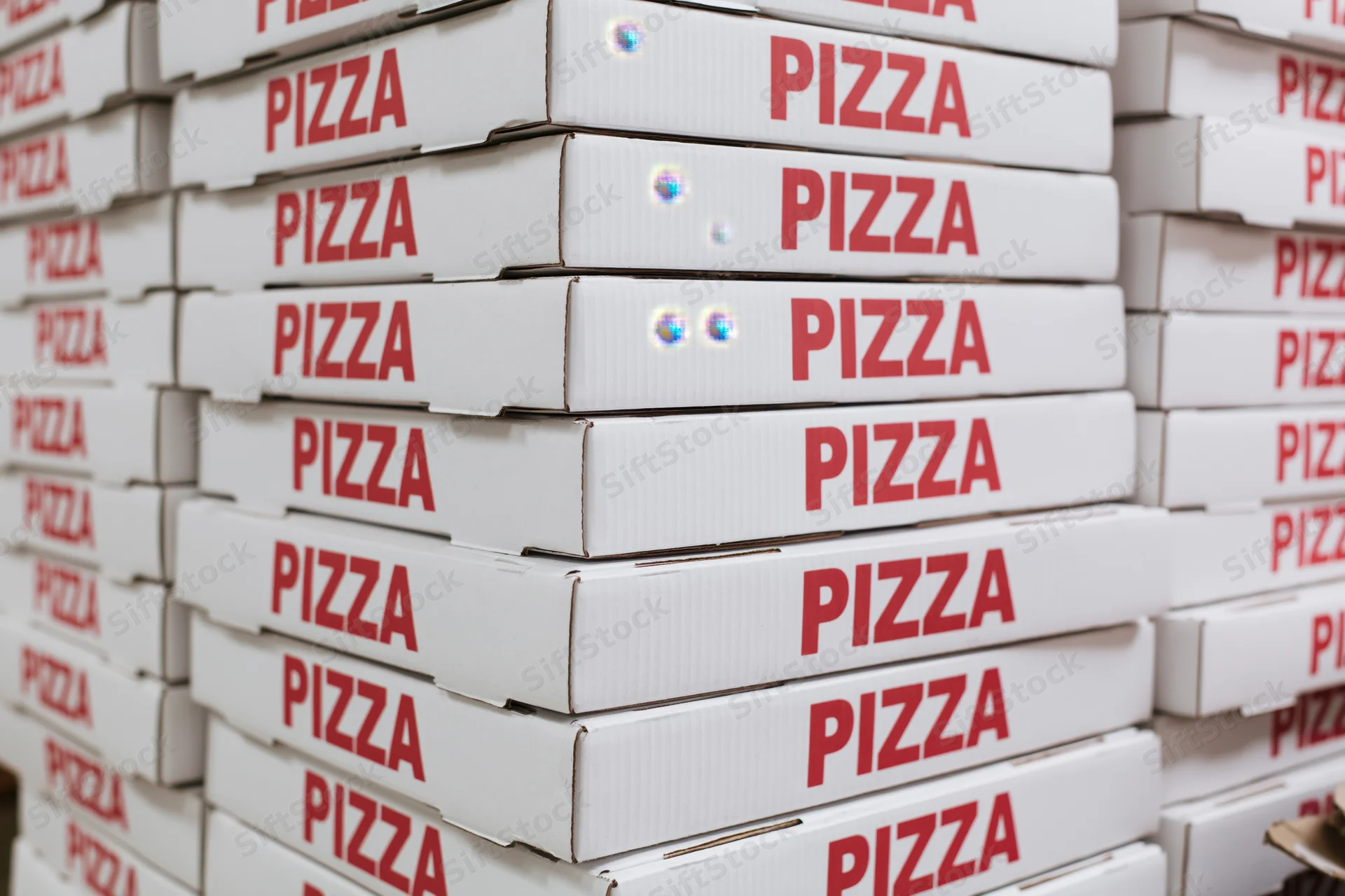 Stacks of white cardboard pizza boxes arranged in rows for delivery or storage