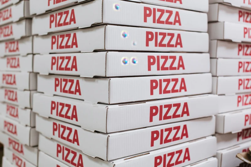 Stacks of white cardboard pizza boxes arranged in rows for delivery or storage