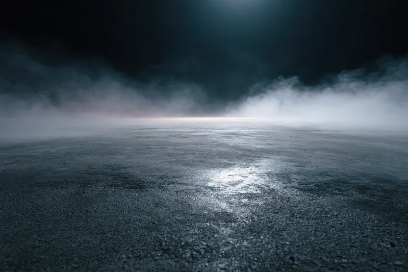 Dark industrial space with fog over wet concrete floor under spotlight