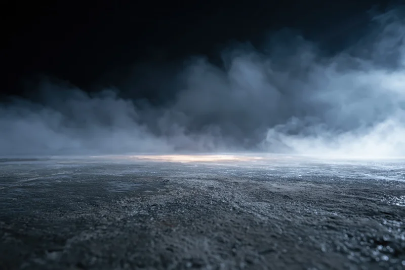 Dark industrial space with smoke rising over empty concrete floor