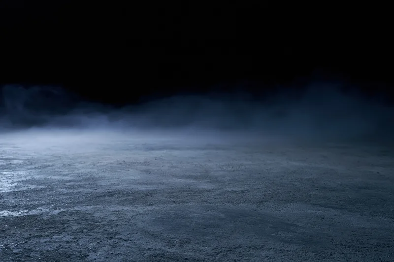 Dark concrete floor with low-lying smoke drifting across the surface at night