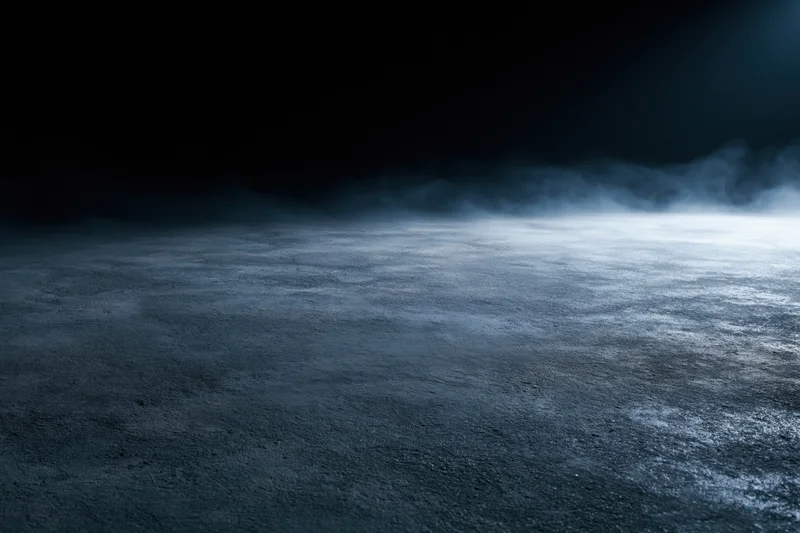 Dark concrete floor with drifting smoke in dim industrial space
