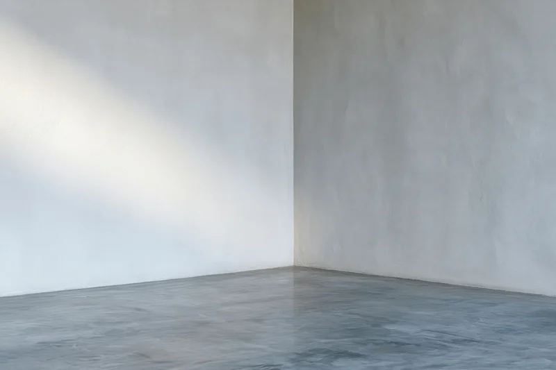 Minimalist interior corner with smooth concrete walls and gray floor