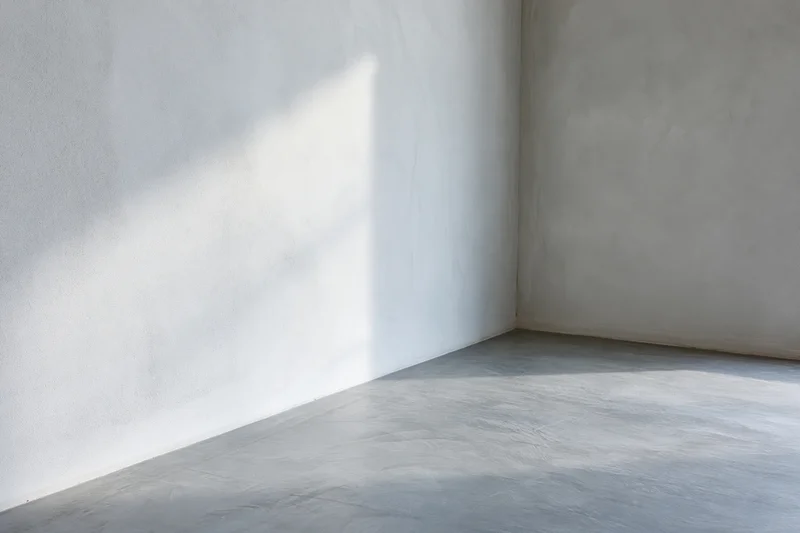 Empty minimalist room with bare concrete walls and smooth floor in corner view