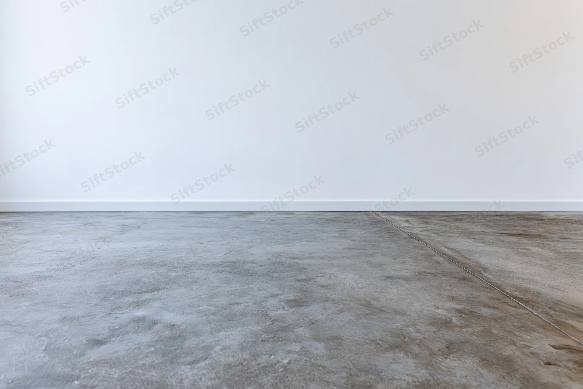 Empty room with bare concrete floor and smooth white wall