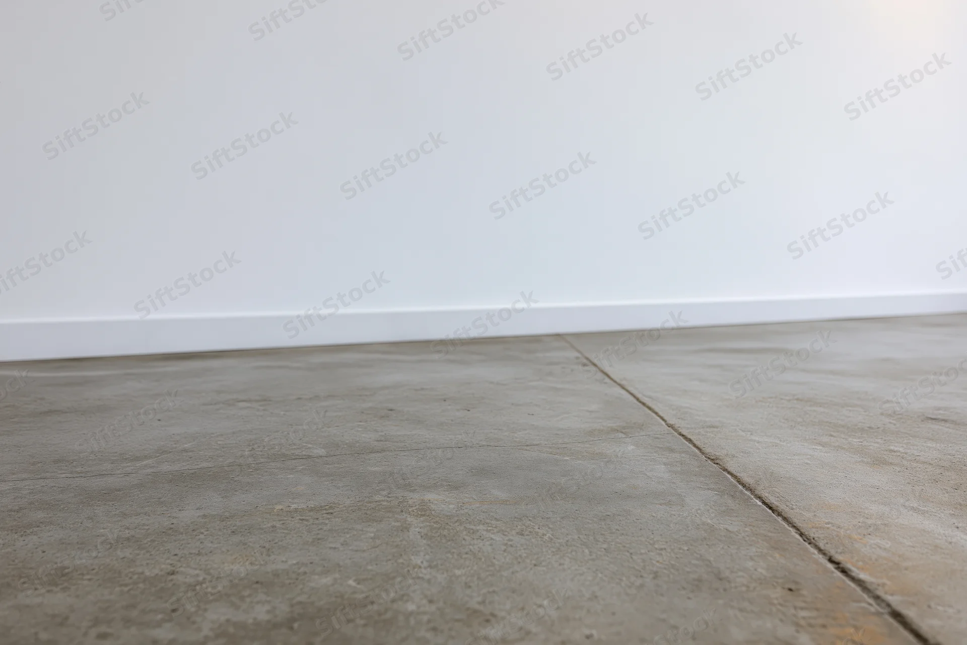 Bare concrete floor meeting smooth white wall in empty room interior