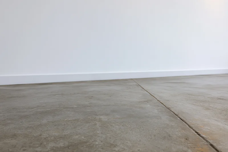 Bare concrete floor meeting smooth white wall in empty room interior