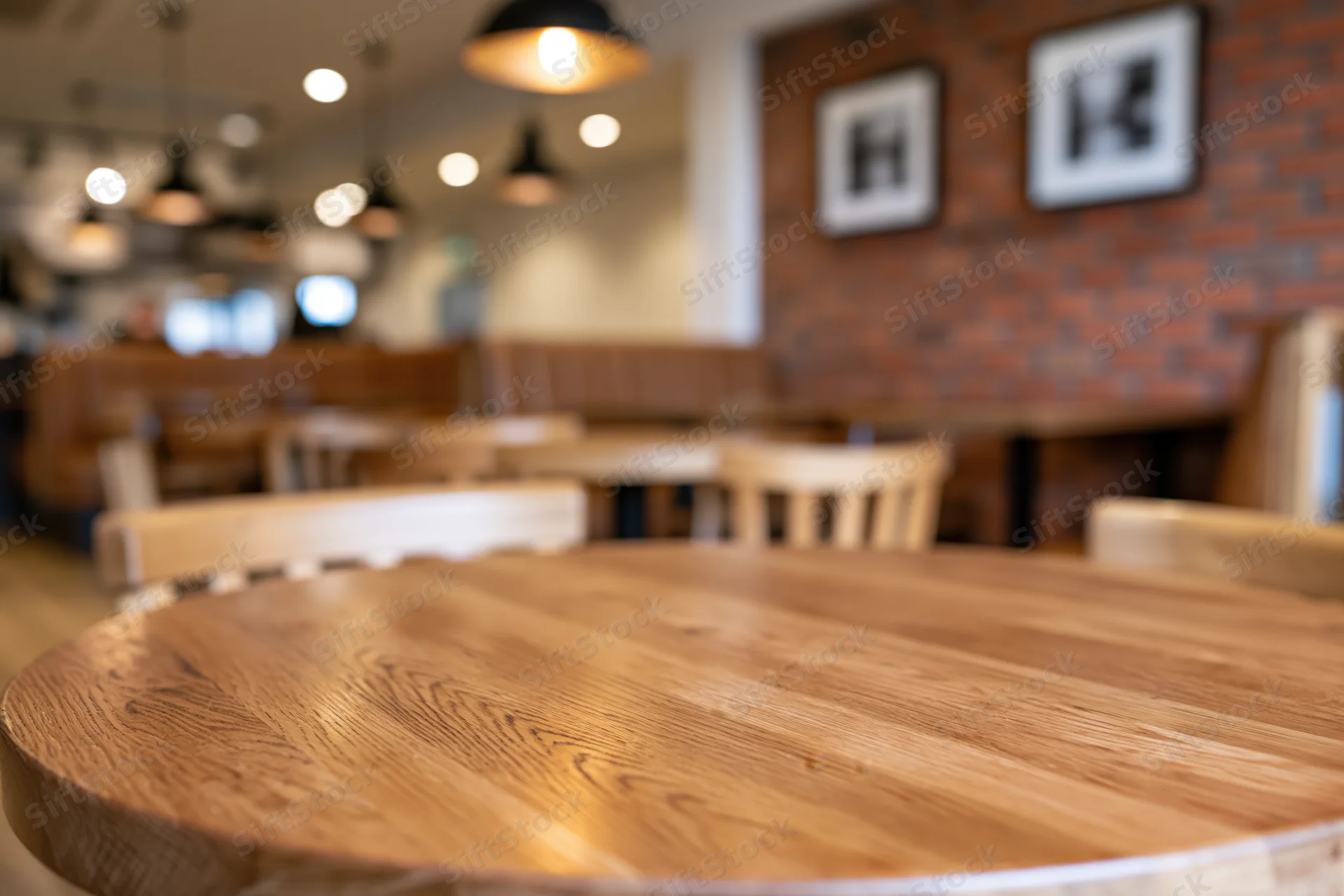Round wooden table in sharp focus with blurred restaurant interior in background