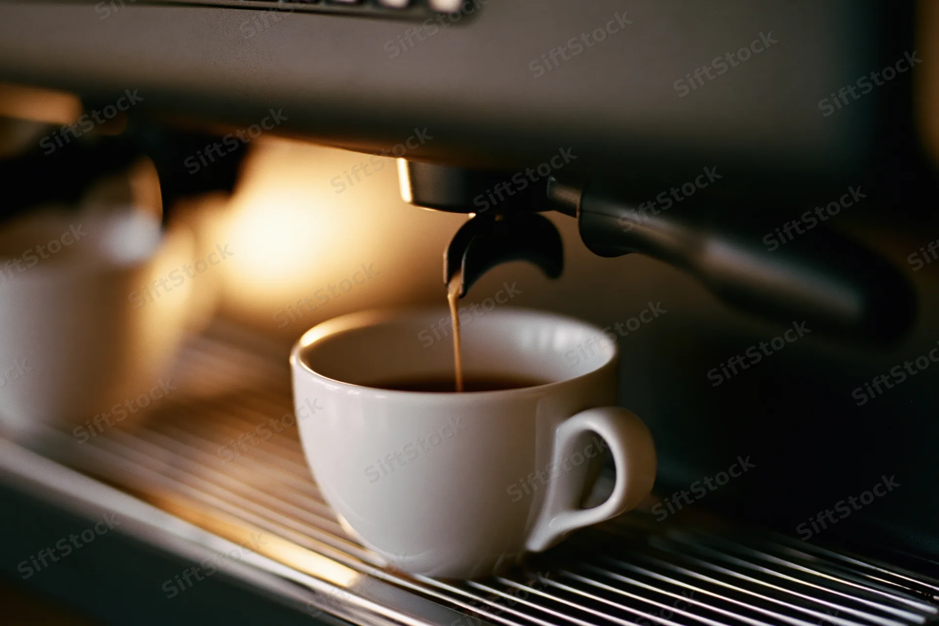 Espresso machine pouring dark coffee into a white ceramic cup on a metal drip tray