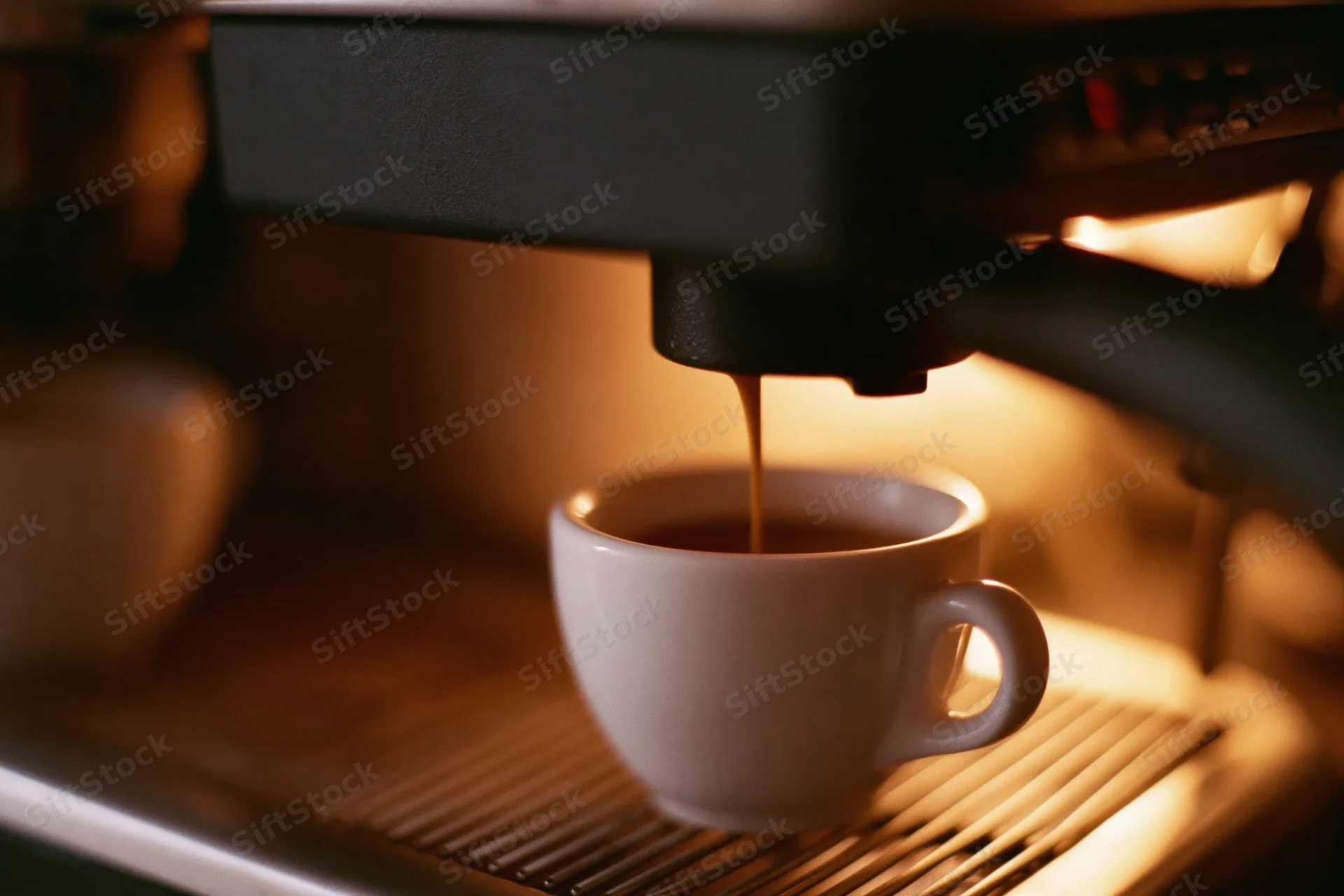 Espresso machine pouring dark coffee into a white ceramic cup on a drip tray