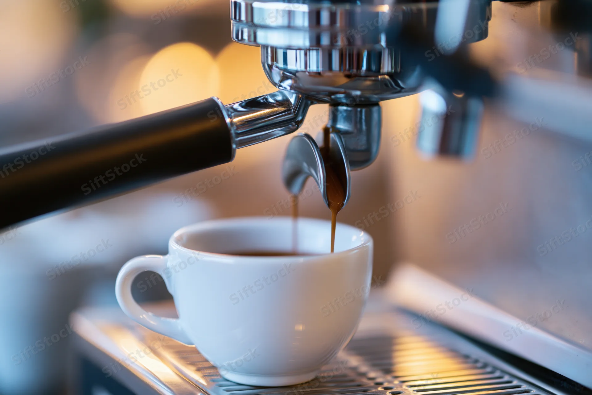 Espresso machine dispensing coffee into a white ceramic cup on a metal drip tray