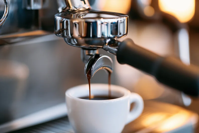Espresso machine extracting double shot into white ceramic cup on countertop