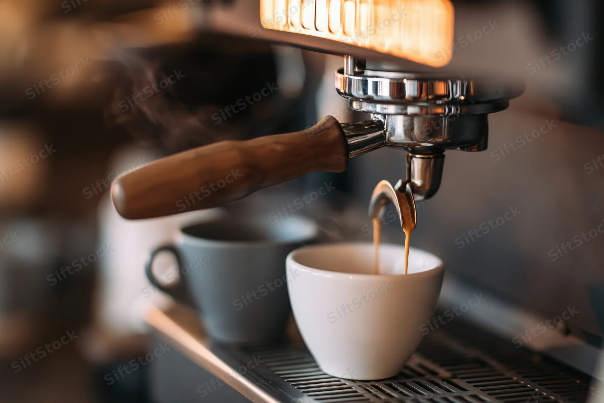 Espresso pouring from a portafilter into a white cup on a coffee machine drip tray