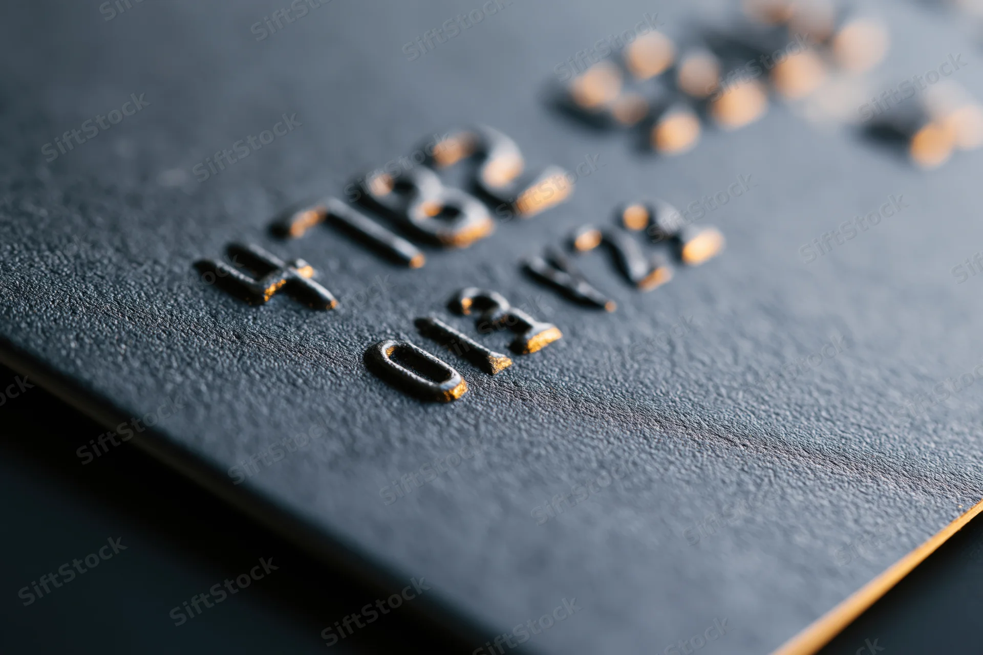 Close-up of embossed numbers on a black matte credit card