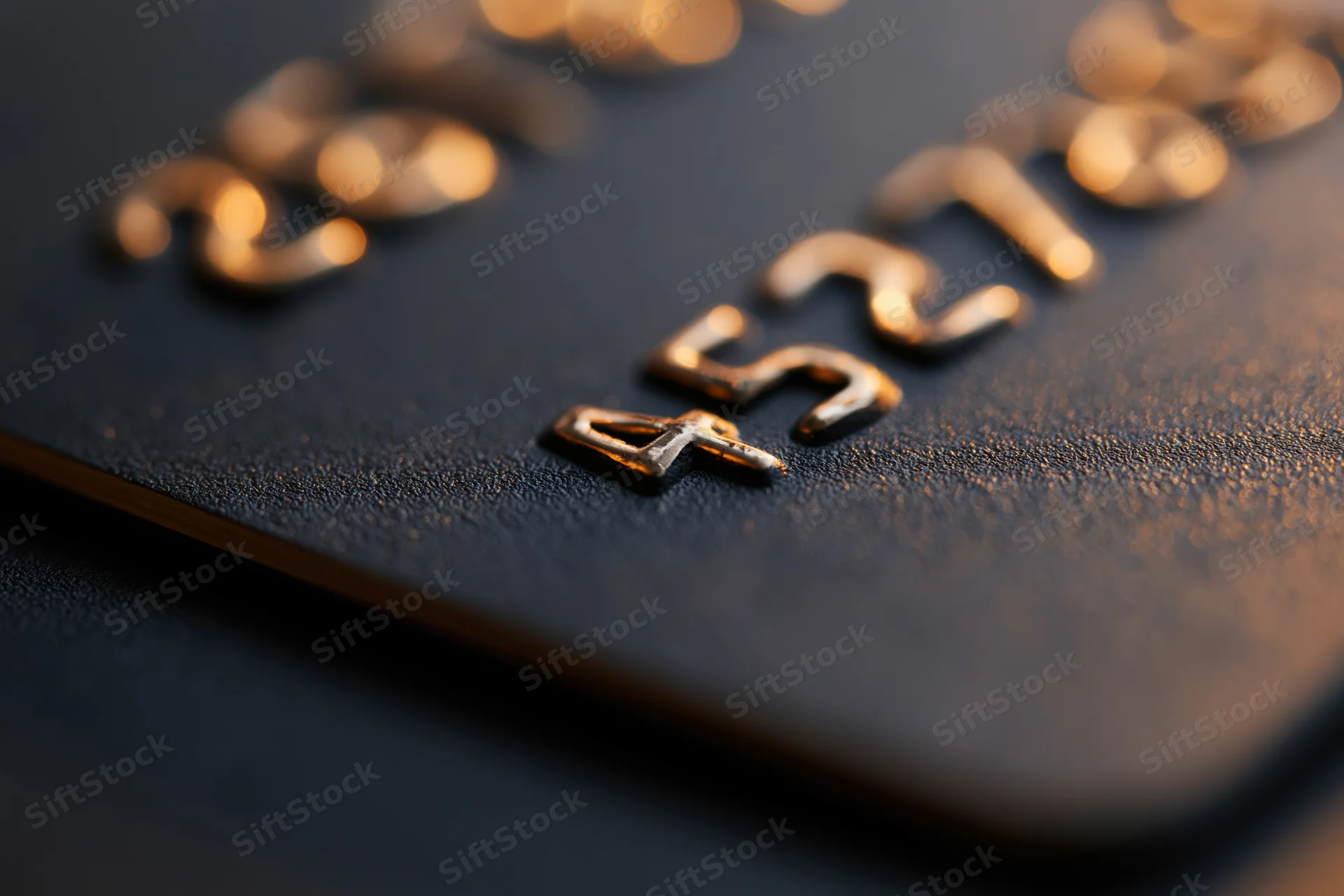 Close-up of embossed numbers on a black matte credit card surface
