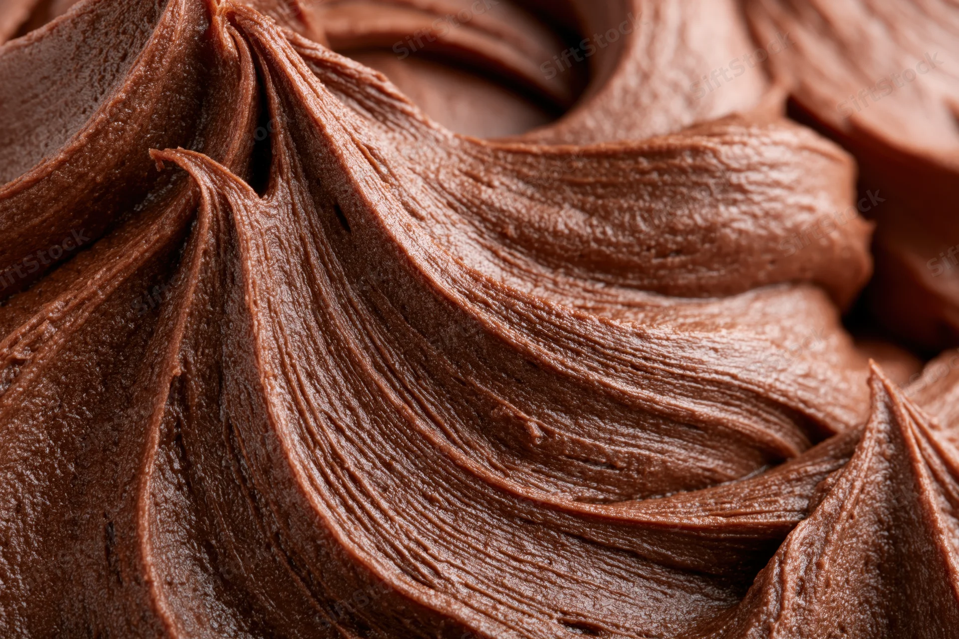 Close-up of dark chocolate buttercream frosting swirls showing rich texture and glossy surface