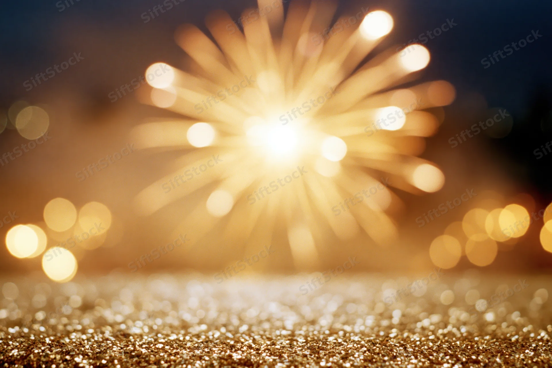 Fireworks bursting in night sky above glittering golden surface