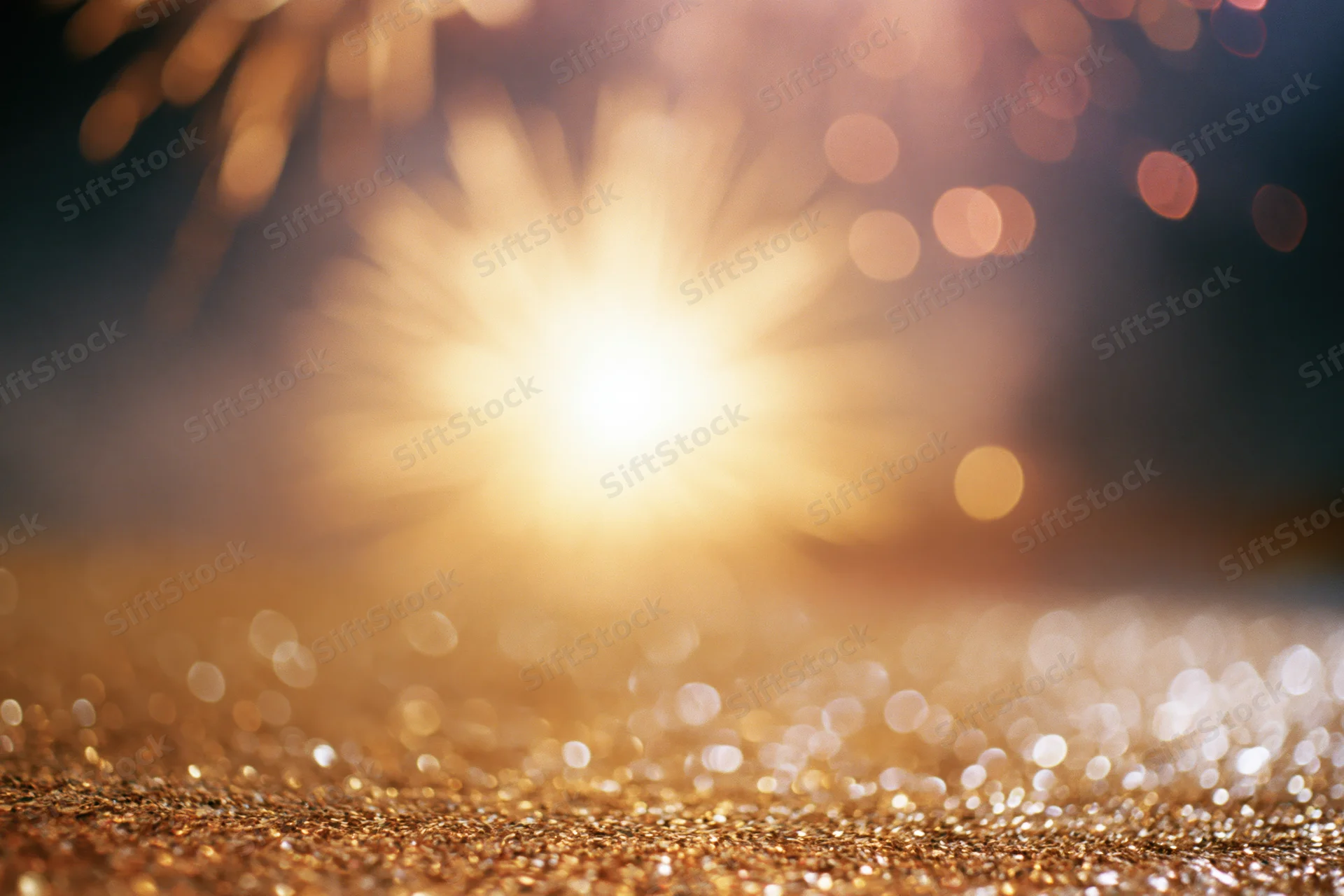 Fireworks bursting in the night sky above a glittering golden surface
