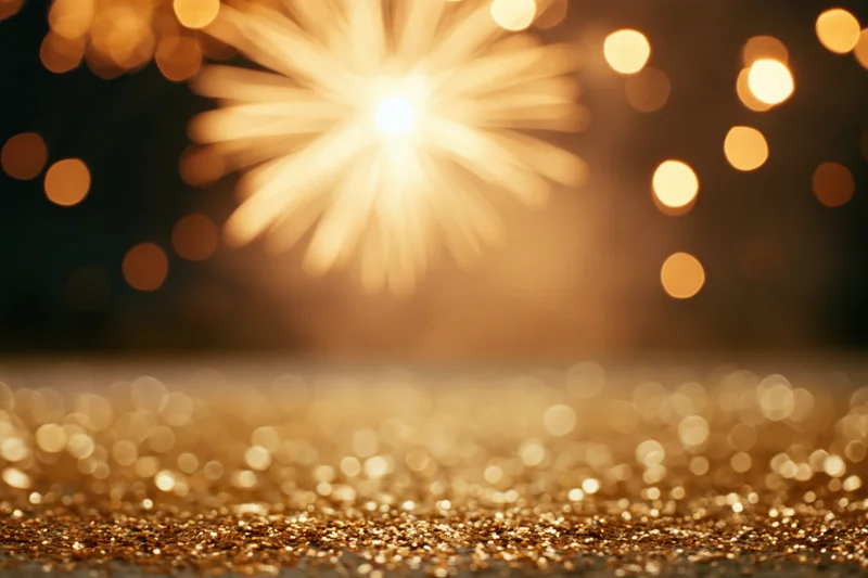 Fireworks bursting in the night sky above a glittering golden surface