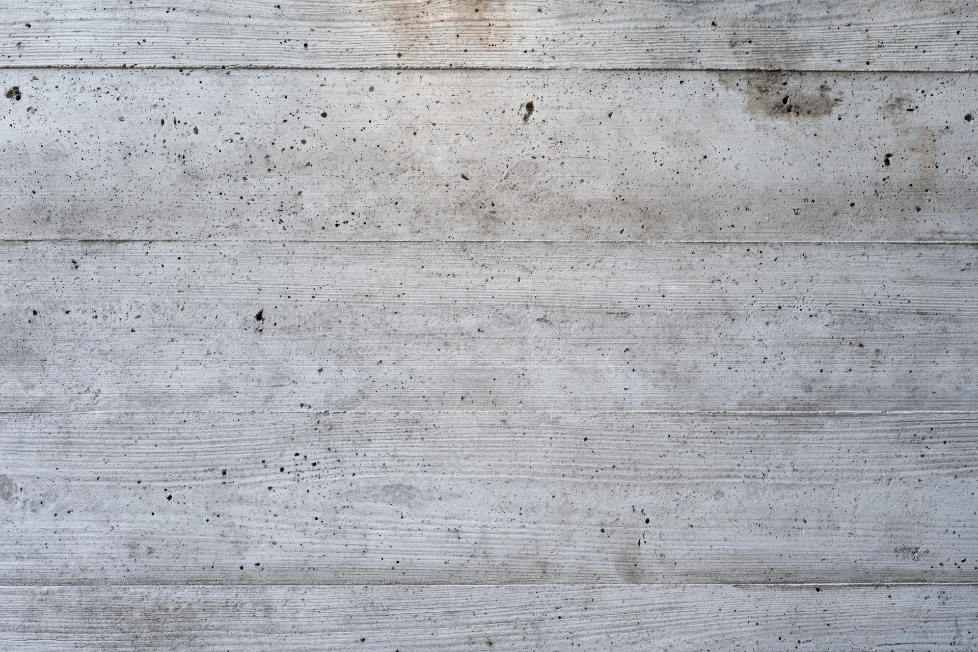 Flat concrete wall surface with horizontal lines and weathered texture filling the frame