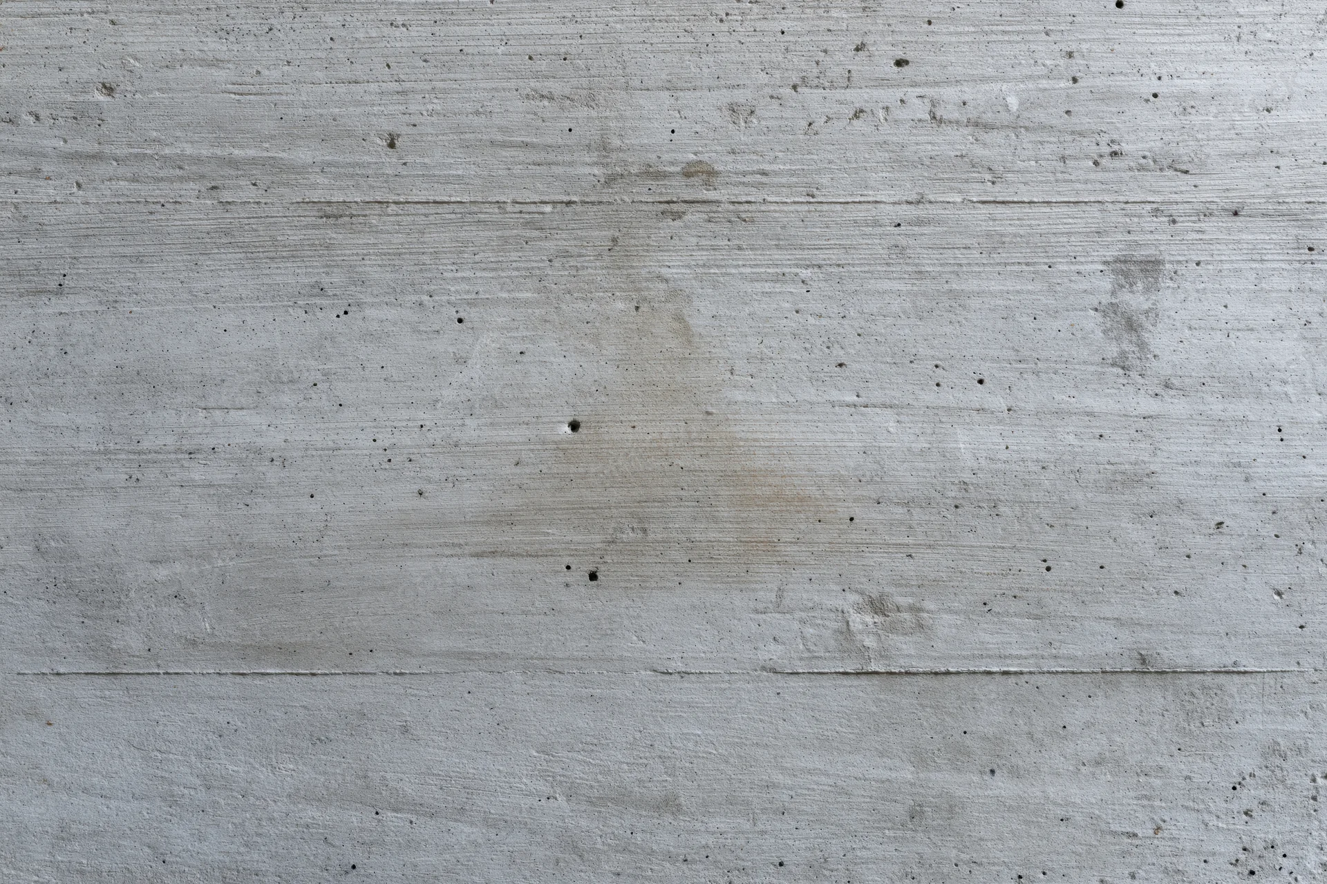 Flat concrete wall surface with horizontal lines and minor imperfections filling the frame