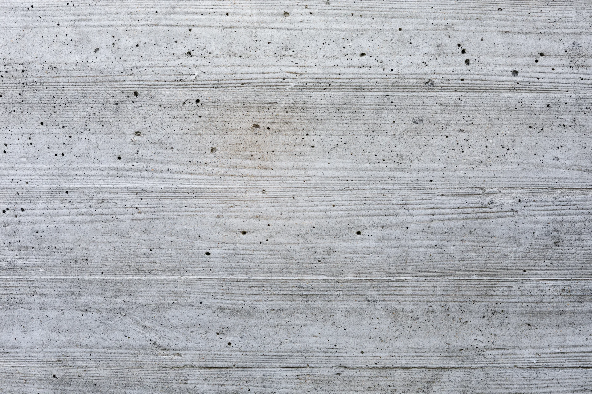 Flat concrete wall surface with horizontal striations and speckled texture filling the frame